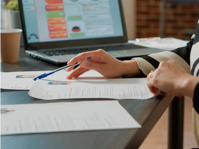Une photo de deux mains féminines regardant un document tenant un stylo.