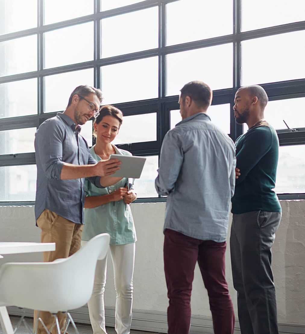 Un groupe diversifié de jeunes adultes se faisant face et regardant une tablette