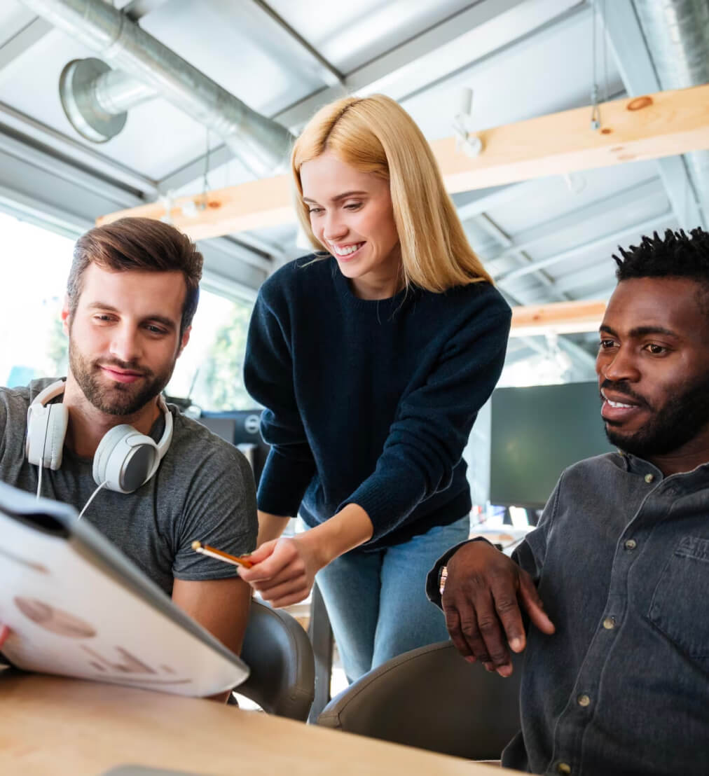 Two men and a woman are looking at documents in an office setting